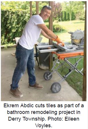 Ekrem Abdic cuts tiles as part of a bathroom remodeling project in Derry Township.